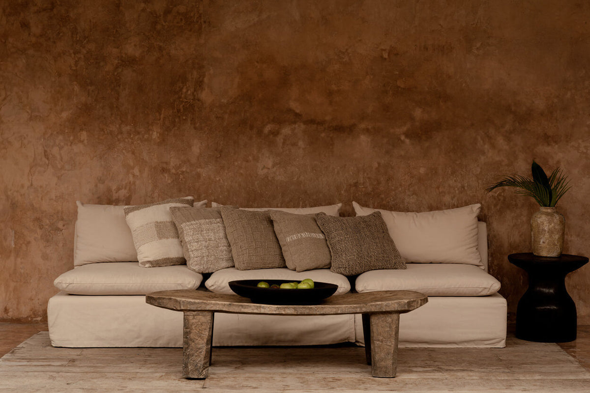 Warm modern living room with beige sofa, rustic coffee table, and earth-toned cushion covers.