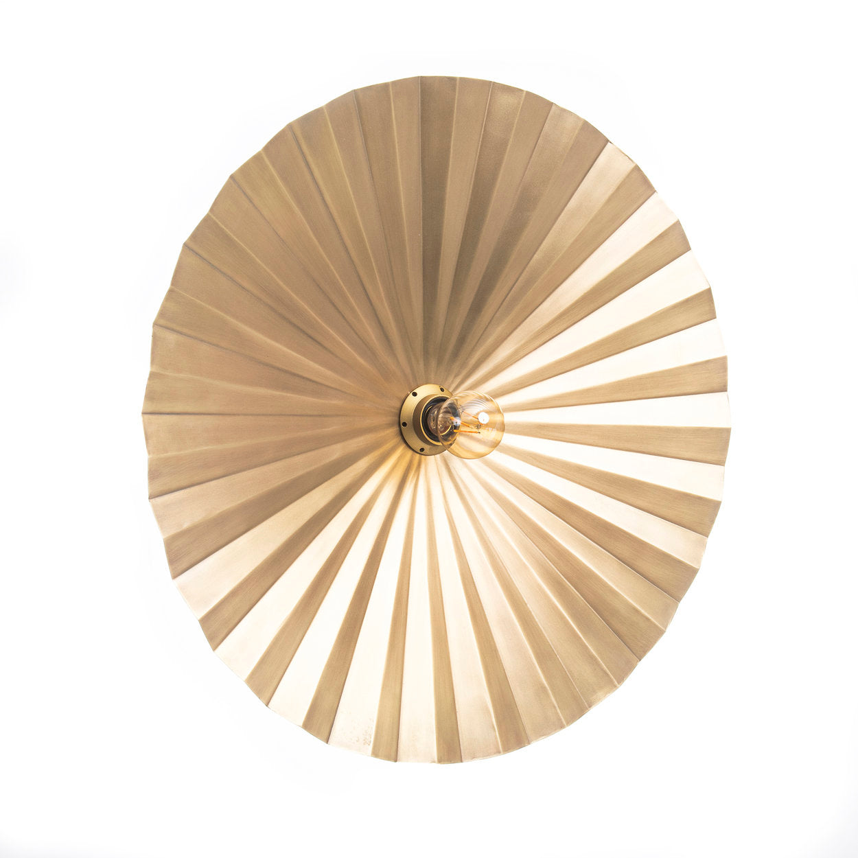Handmade brass wall lamp with a golden finish, shown in a reading corner styled with natural wood and linen fabrics.