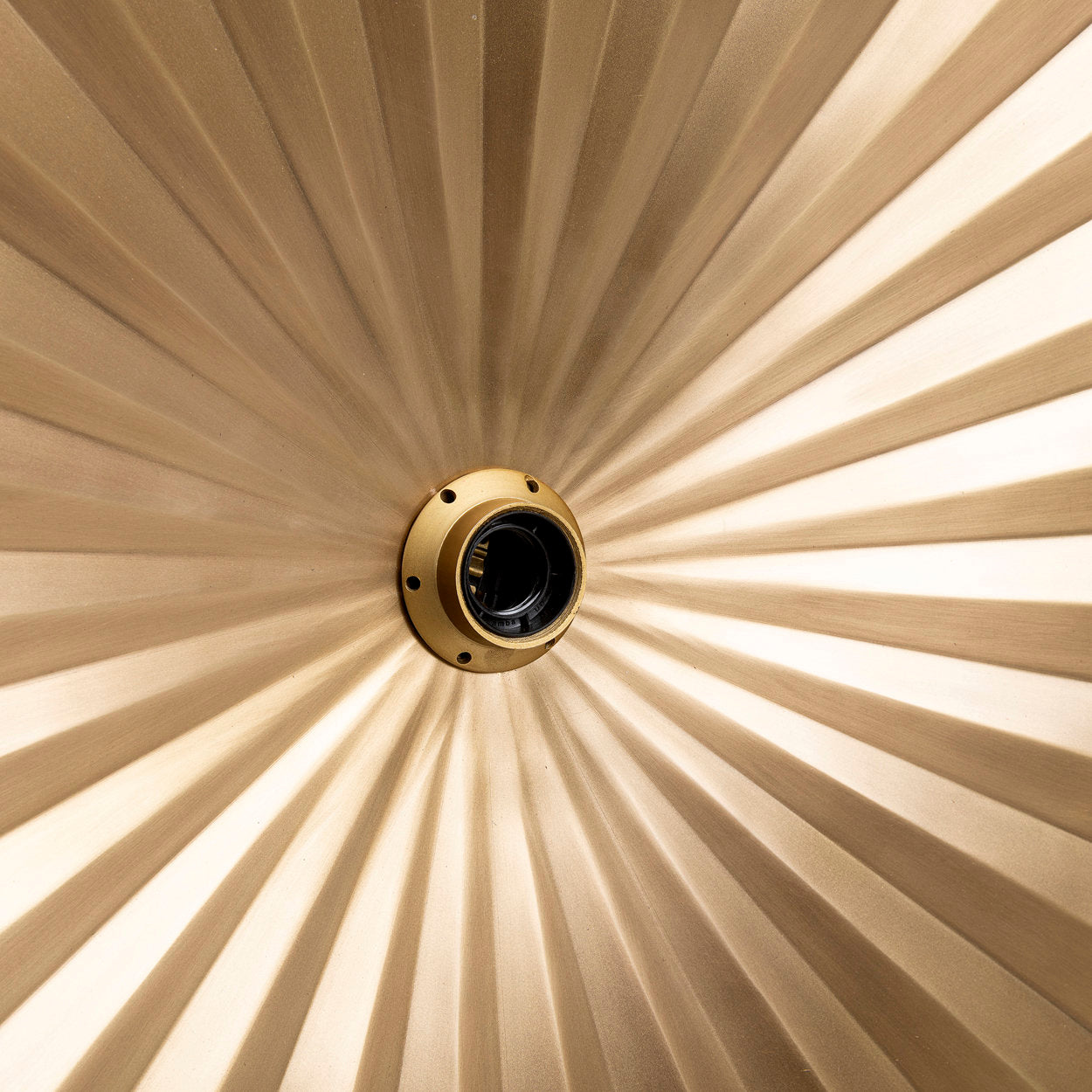 Modern brass wall light mounted in a hallway, casting ambient light while complementing neutral tones and organic textures.