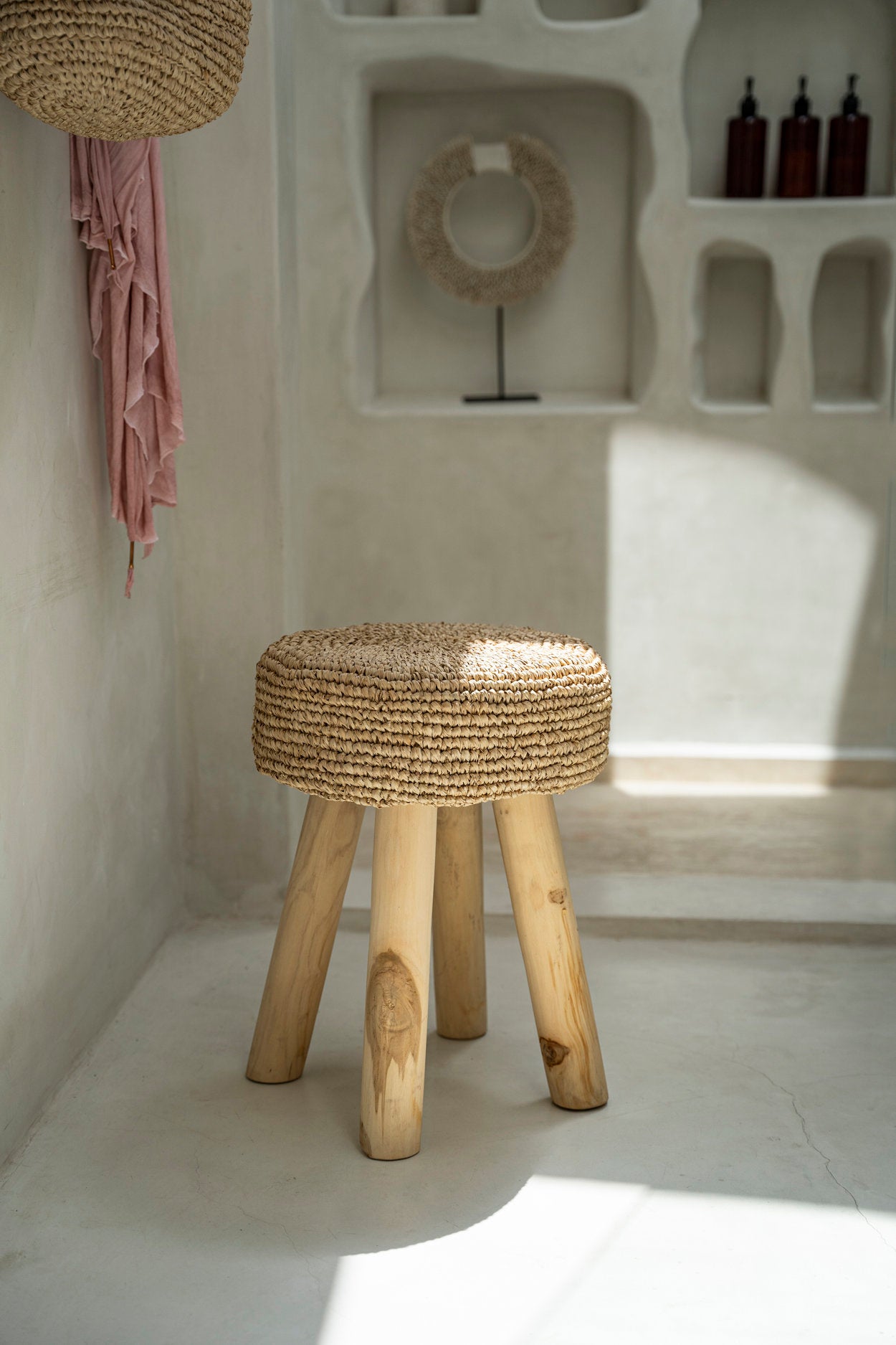 Compact teak stool featuring handwoven raffia for warm interiors