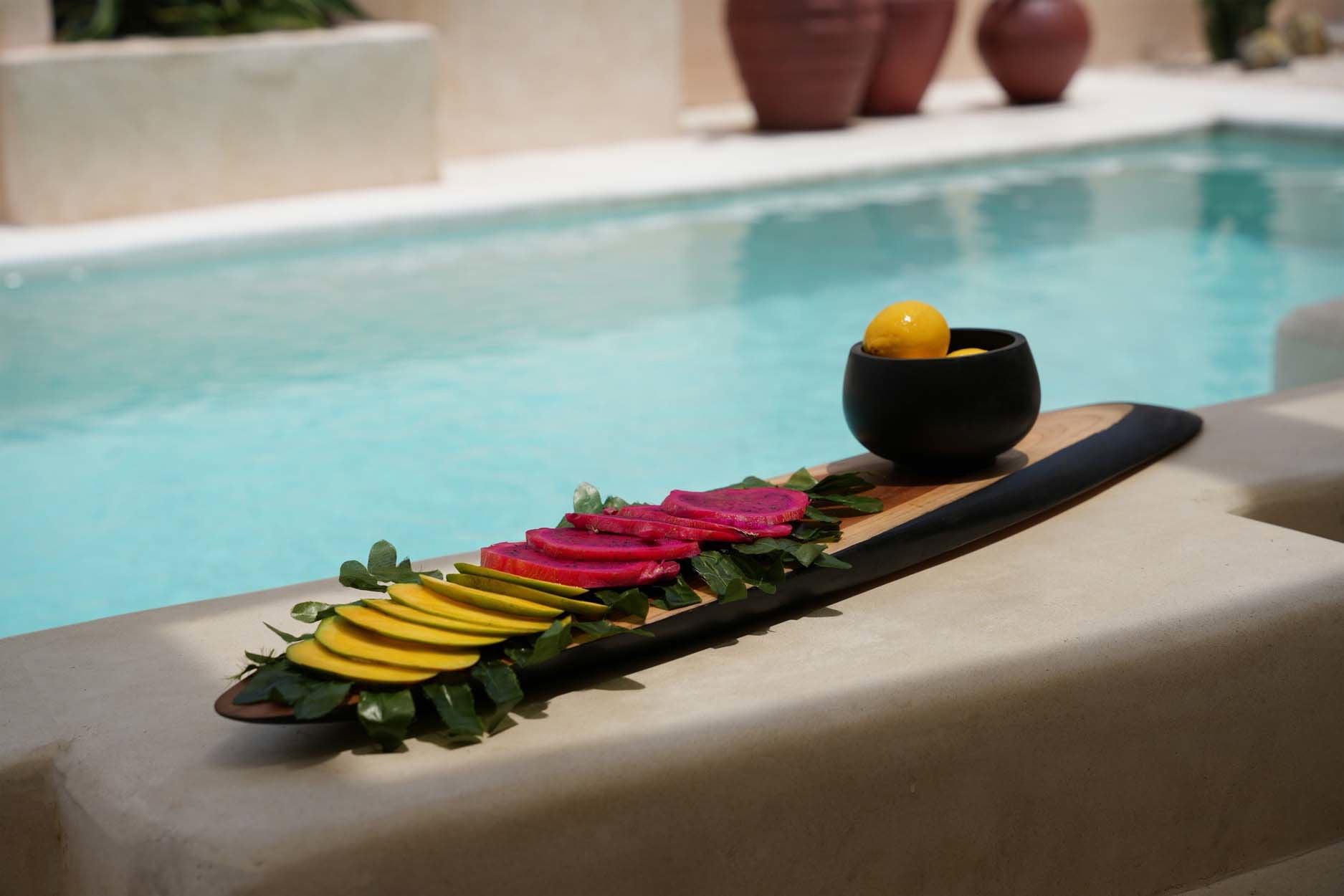 Hand-carved black teak appetizer plate, perfect for cheese boards, fruit displays, or charcuterie spreads.