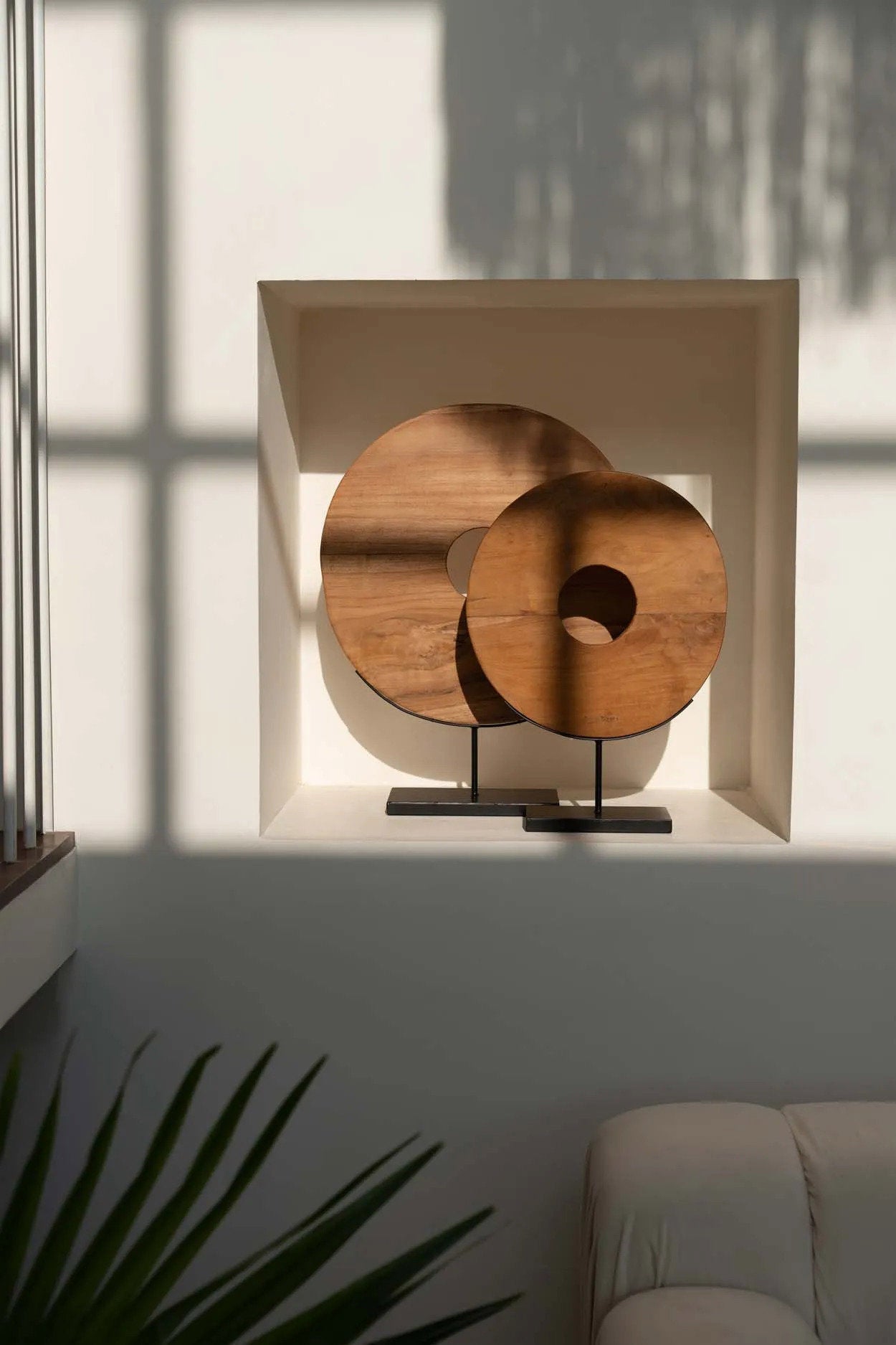 Minimalist teak wood circle ornament with centered cutout on black metal base