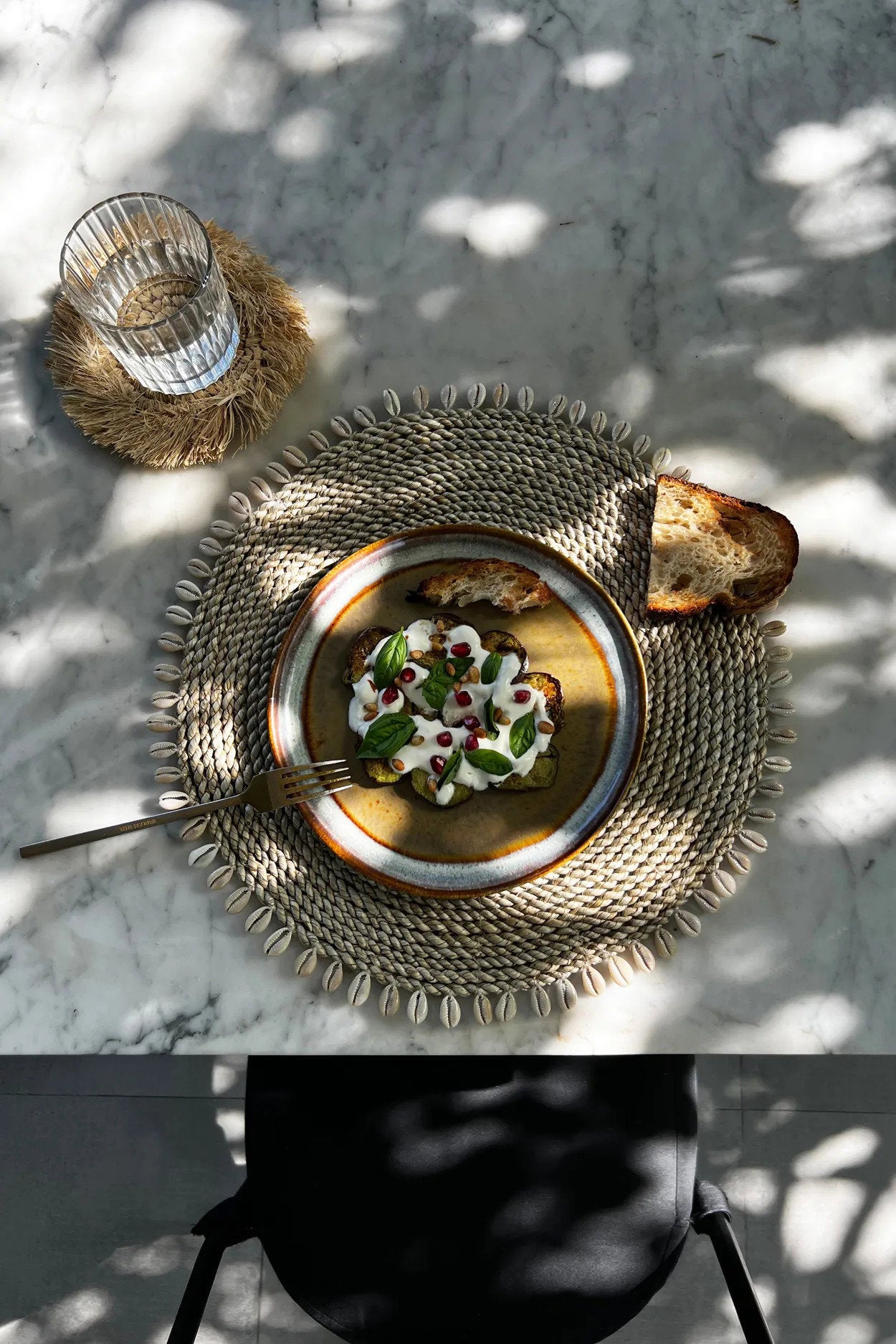 Woven coastal placemat with shells, crafted from natural seagrass for an eco-friendly, stylish table accent.