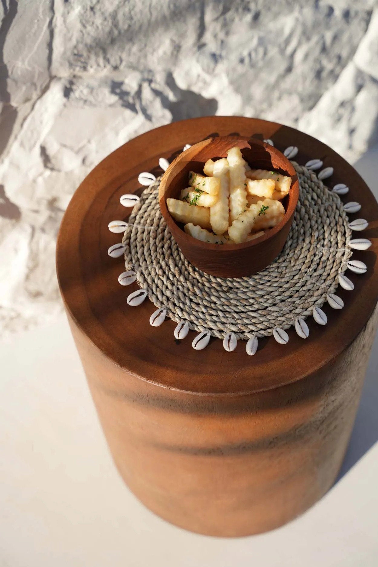 Boho-style raffia coaster with shell accents, blending durability, eco-friendliness, and decorative appeal.