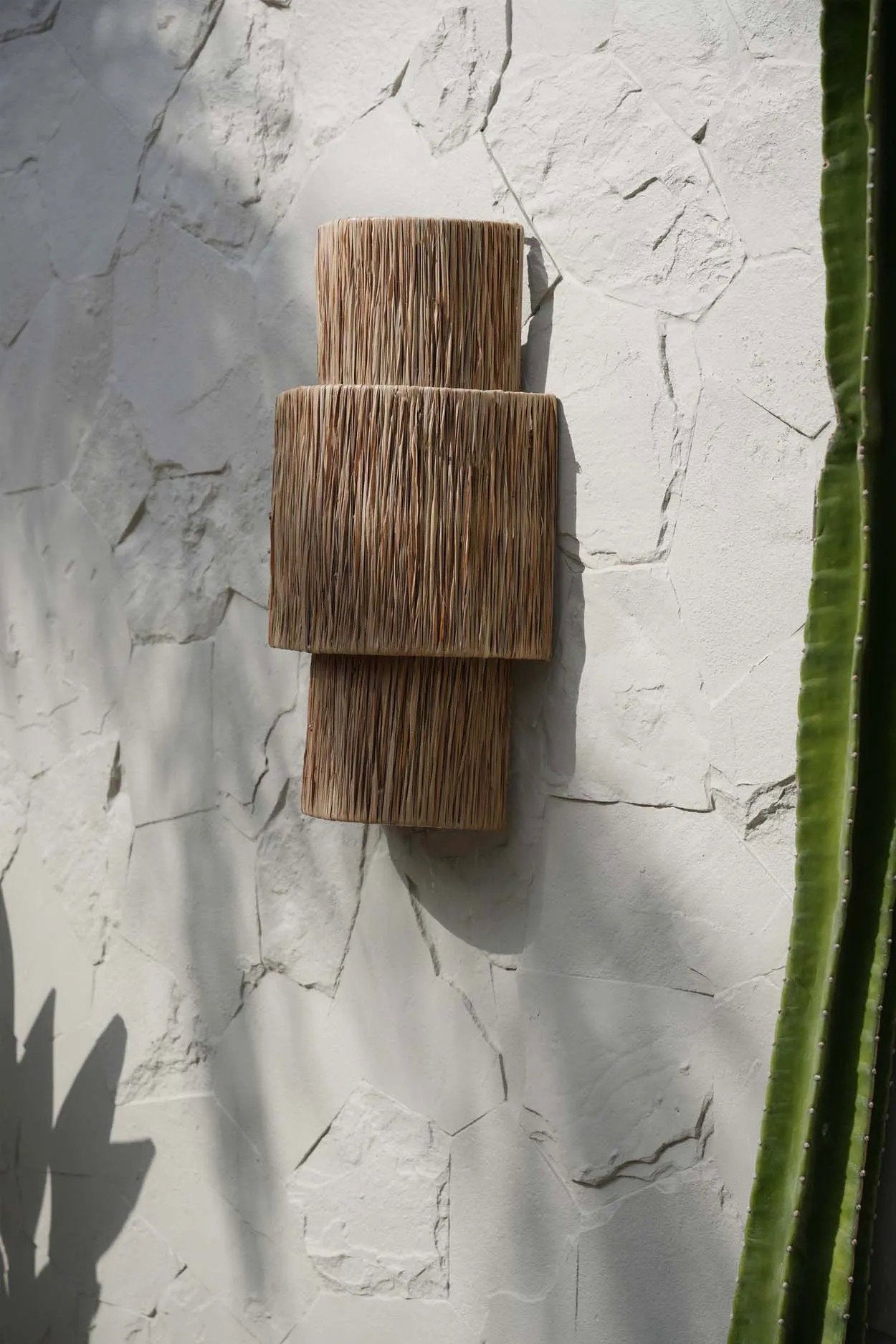 The Ohana Wall Applique in natural sisal, styled in a hallway, adding cozy ambient lighting and textural depth to the wall.