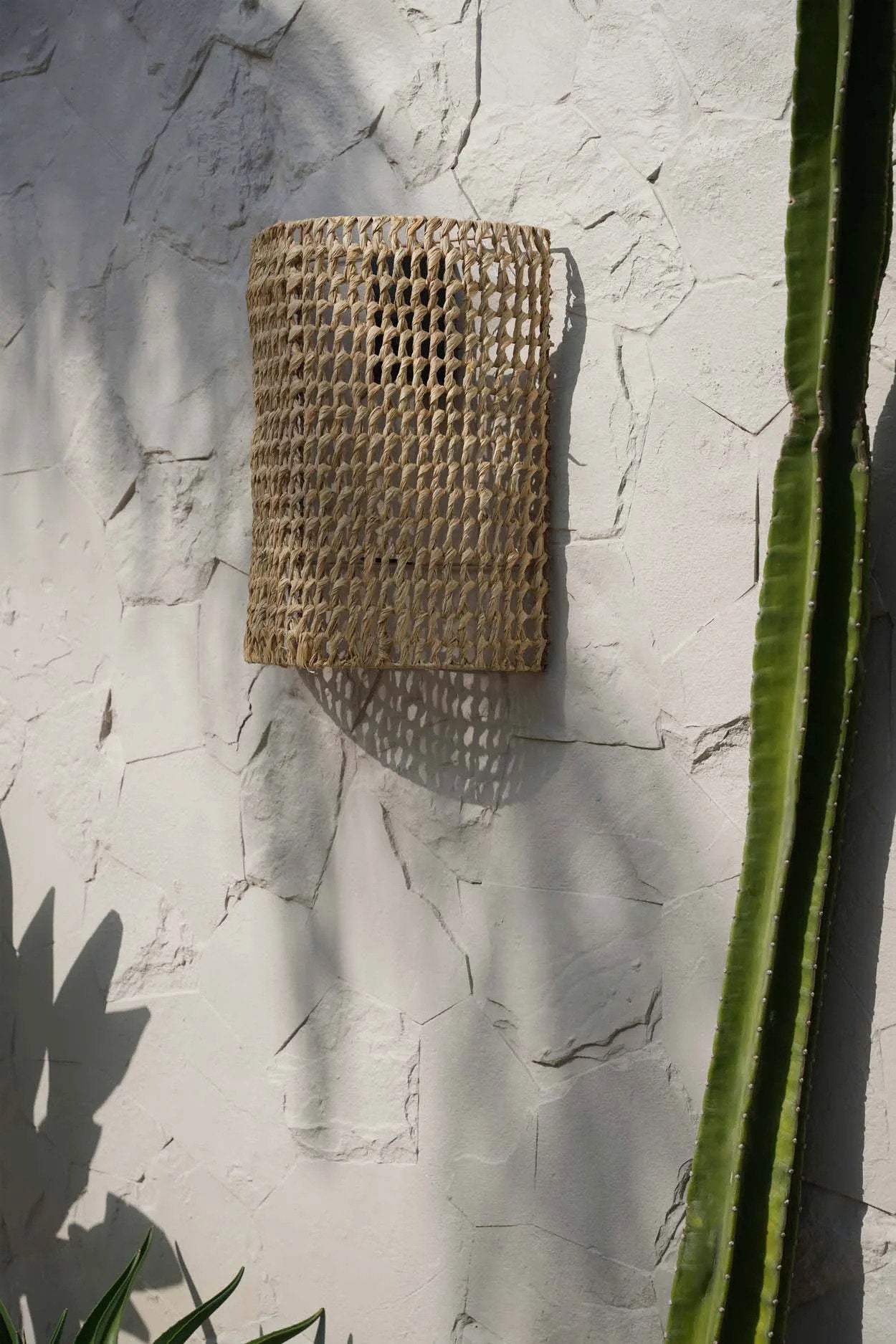 The SiriKit Wall Applique, a handmade rattan wall lamp with natural texture, ideal for creating cozy atmospheres in entryways or living rooms.