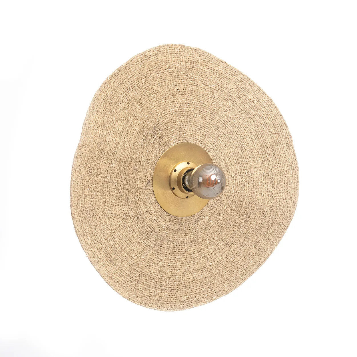 Handmade brass wall sconce combining iron and woven grass materials, shown mounted in a coastal-inspired living space.