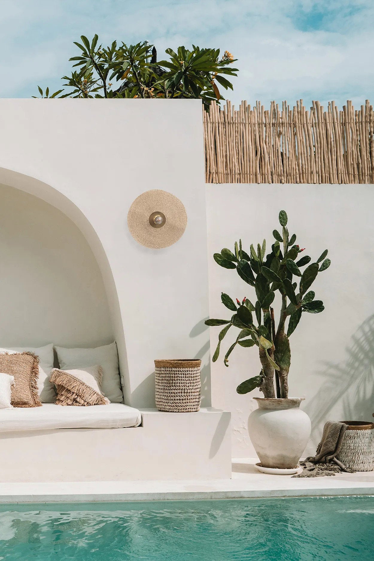 The Let’s Groove Wall Lamp in natural brass, featuring a unique curved design with handwoven grass texture for a cozy ambient glow.