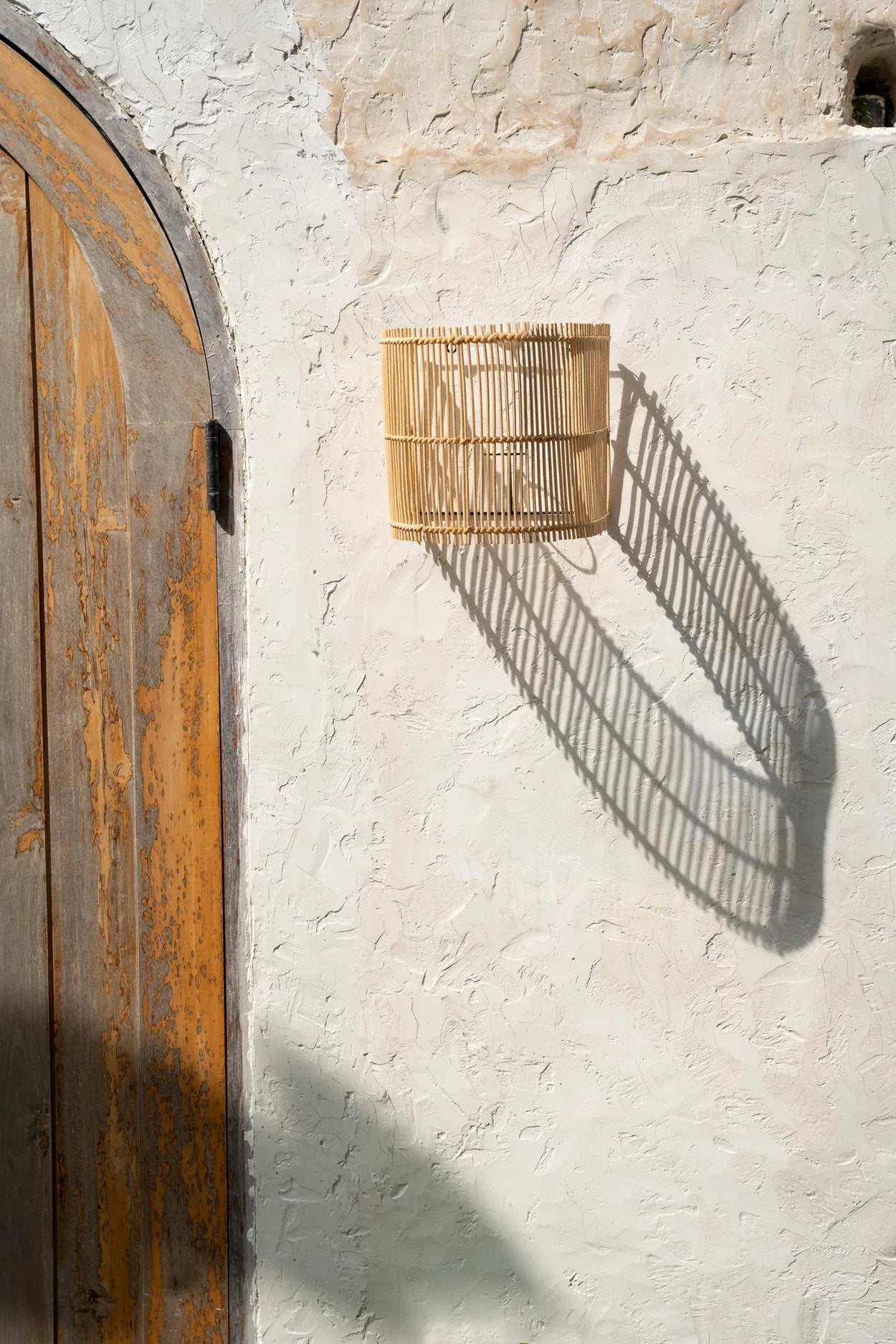 Handmade rattan wall lamp styled in a cozy hallway, casting warm light and creating an inviting atmosphere.