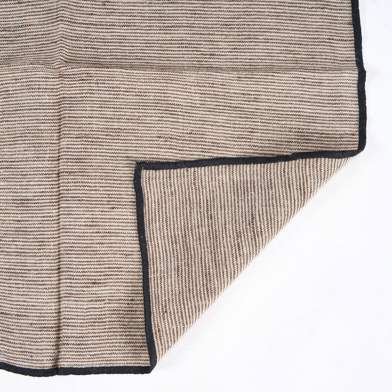 Natural black linen napkin placed beside neutral ceramic tableware for an understated rustic look.