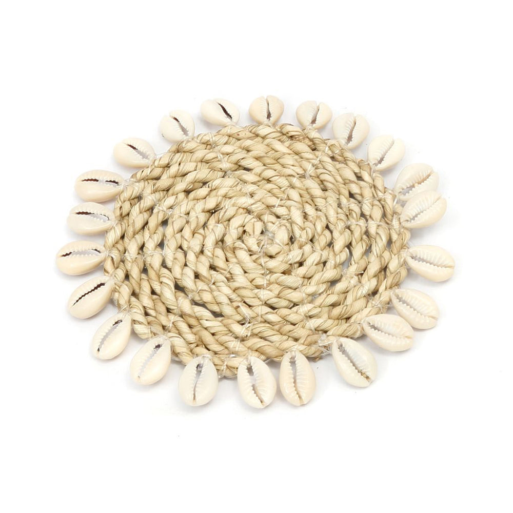 A dining table coaster hand-woven from twisted seagrass fibres and adorned with real white cowrie shells.
