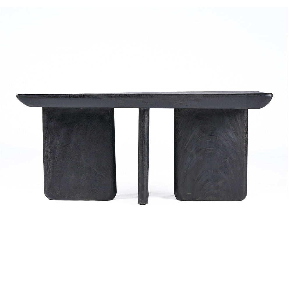 The black coffee table crafted from solid mango wood stands with sculptural balance, its deep tone adding quiet contrast to a soft, modern interior.