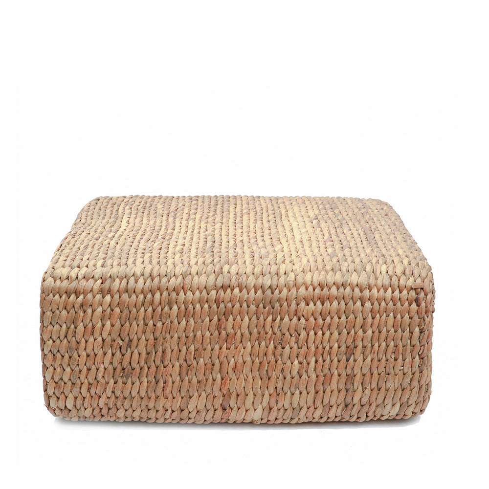 A square natural fibre coffee table pouffe with artisanal braided texture in a warm straw hue.