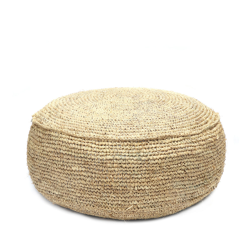 A hand woven raffia pouffe in a natural tone with intricate weave detail.