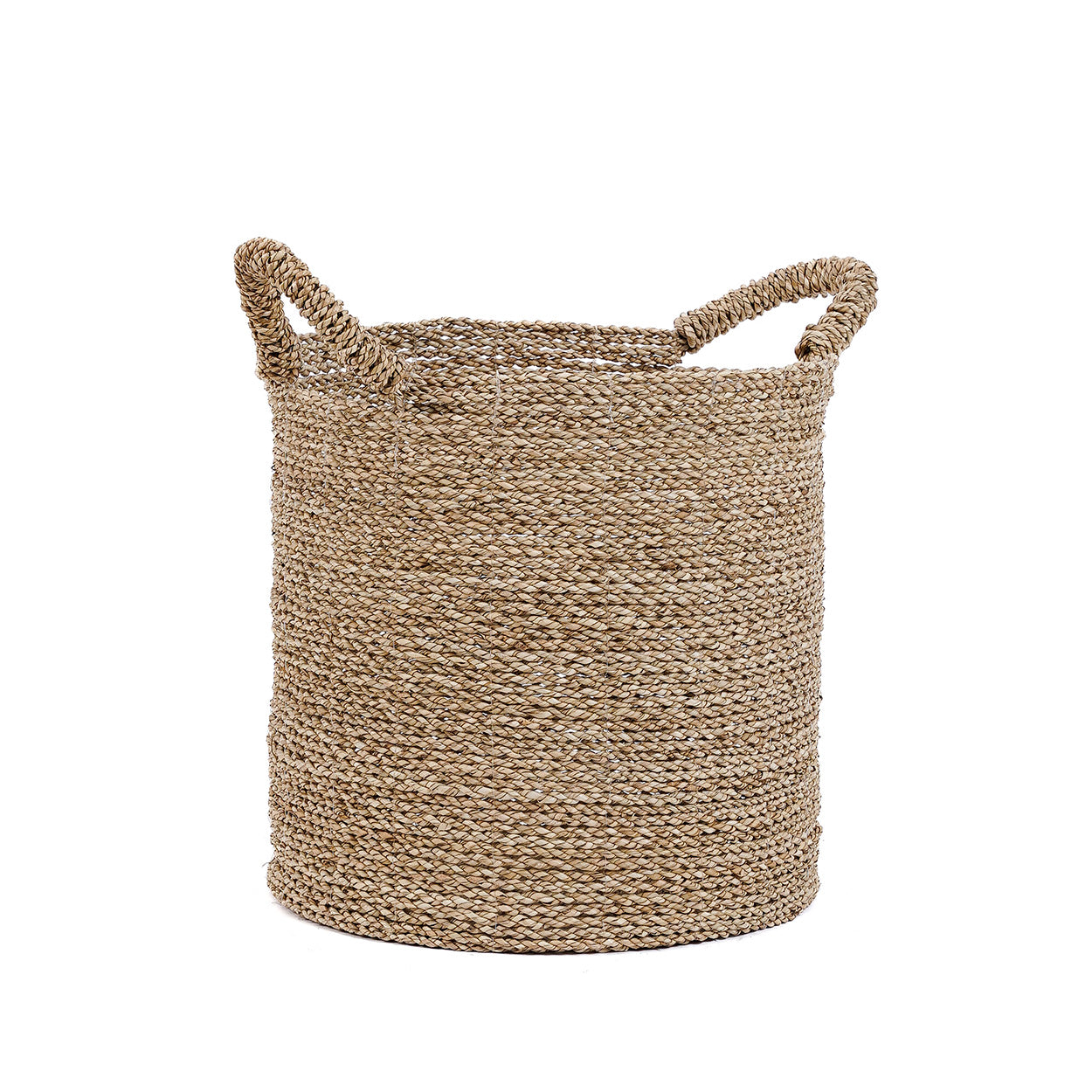 A tall seagrass storage basket handwoven in natural fibers, its softly textured surface and rounded form bringing quiet warmth to the space.