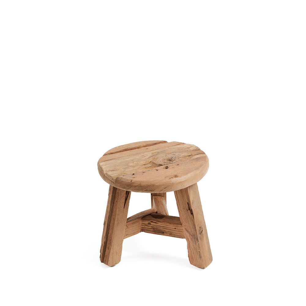 A mini handmade wooden stool with weathered character on the seat and a sturdy three-legged stance.