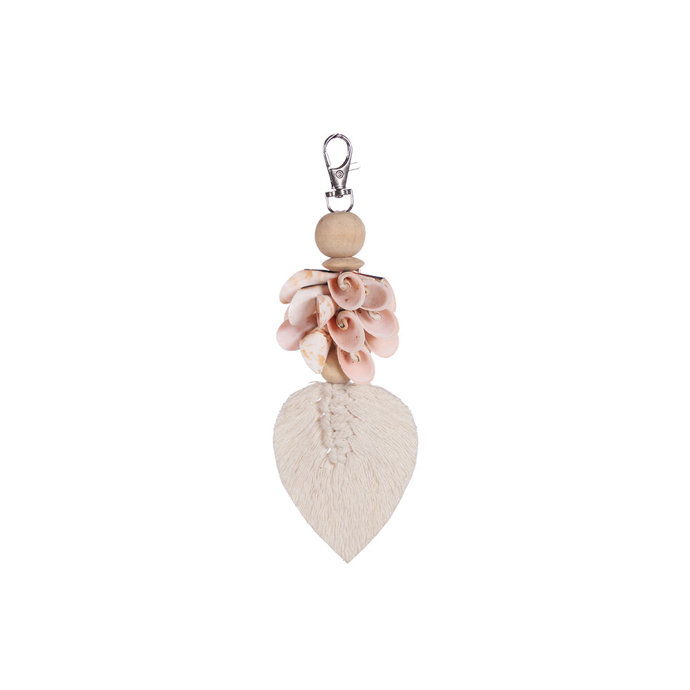 A pink white coastal keychain made from cowrie shells, a wooden bead, and a leaf-shaped cotton.