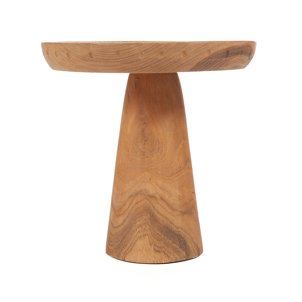 A teak wood cake stand with a hand-turned surface and bold pedestal base, showcasing the wood's natural, rhythmic grain.