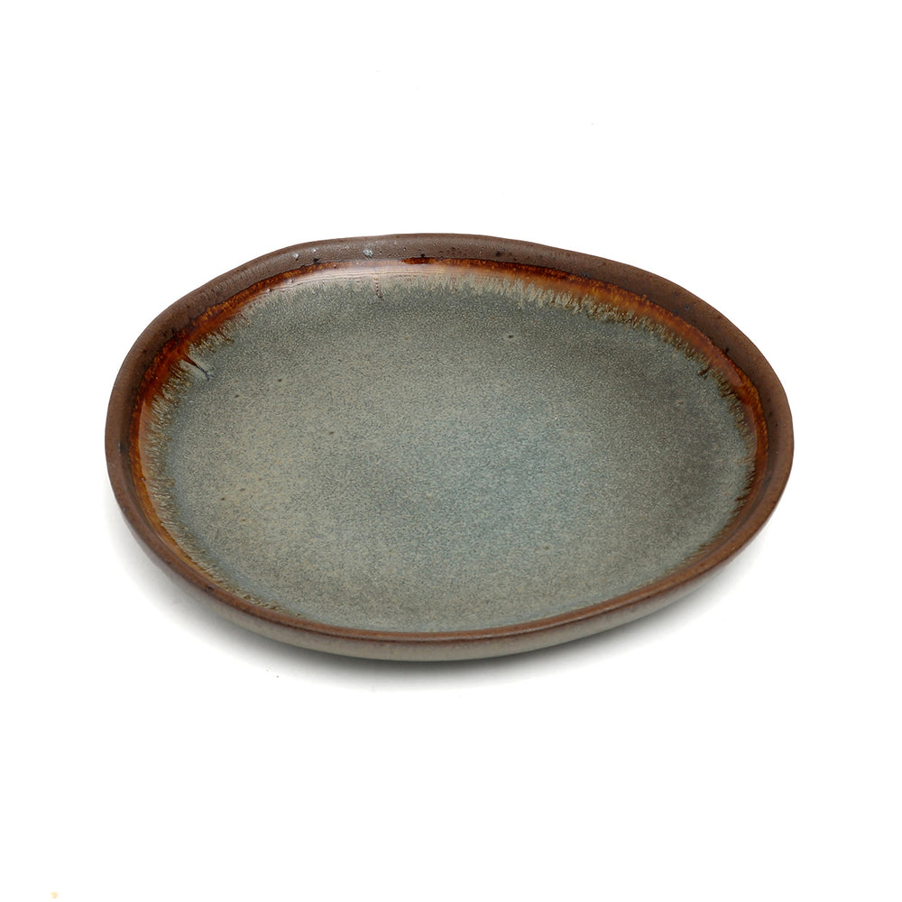 An appetizer plate with reactive glaze featuring an organically uneven rim, adorned with a soft, earthy gradient glaze.