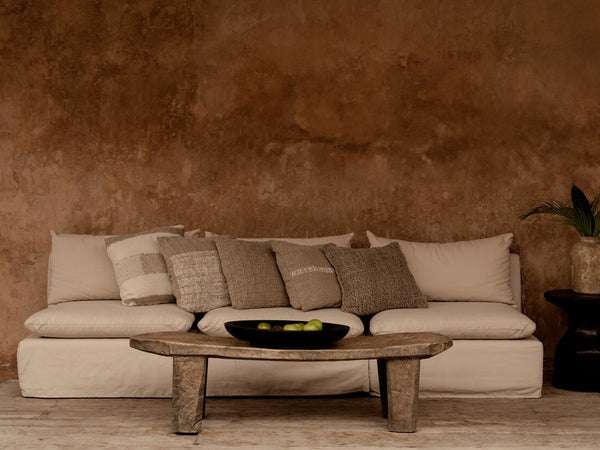 Warm modern living room with beige sofa, rustic coffee table, and earth-toned cushion covers.