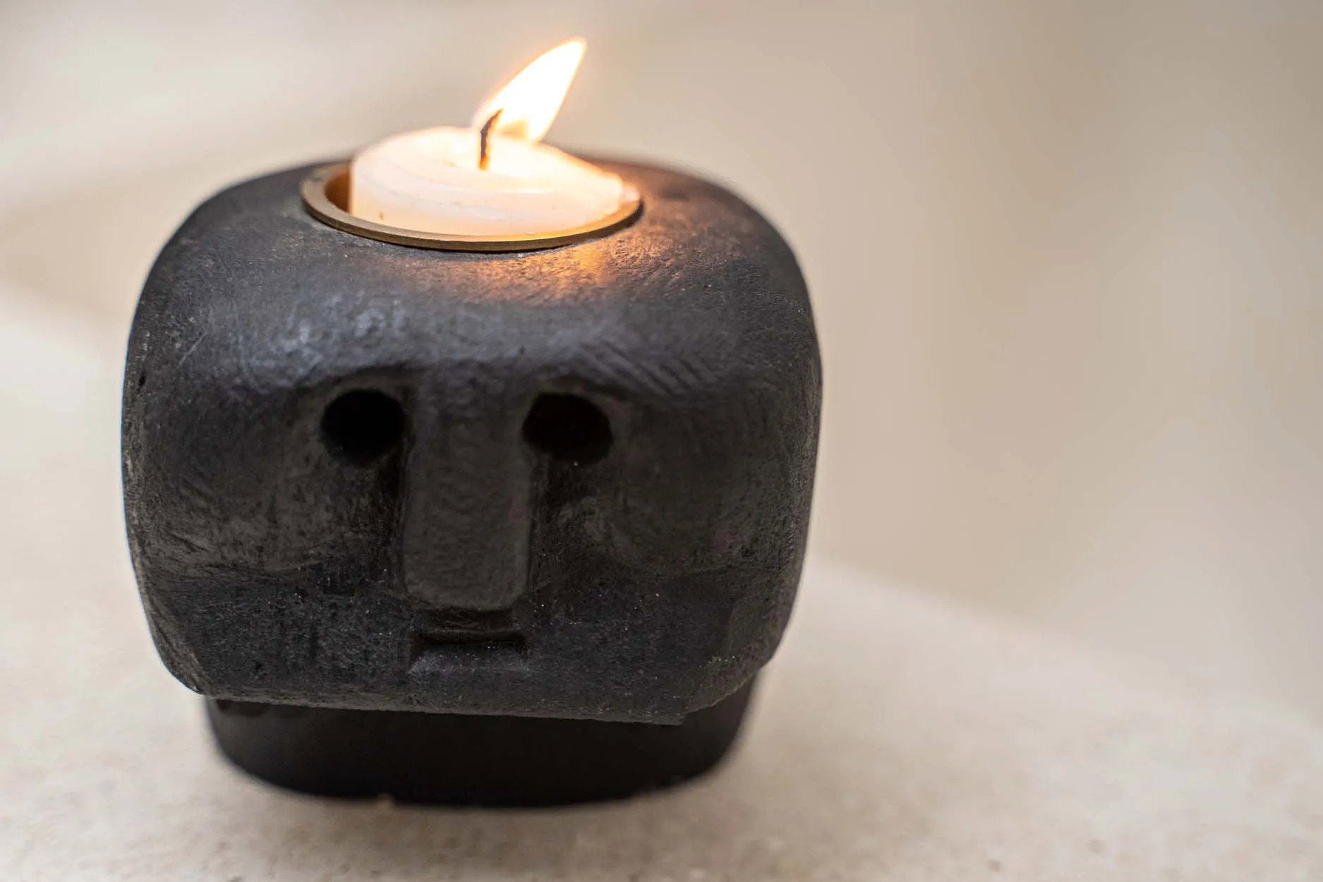 Boho-style sandstone candle holder with intricate facial carving