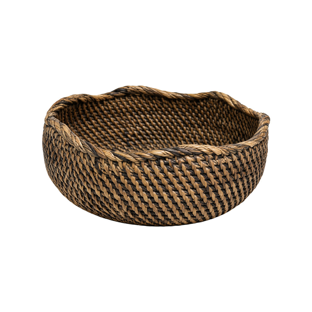 A wicker rattan bowl in a natural brown colour, shaped as a rounded bowl with a wavy rim.