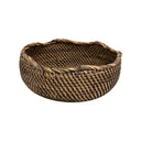 A wicker rattan bowl in a natural brown colour, shaped as a rounded bowl with a wavy rim.