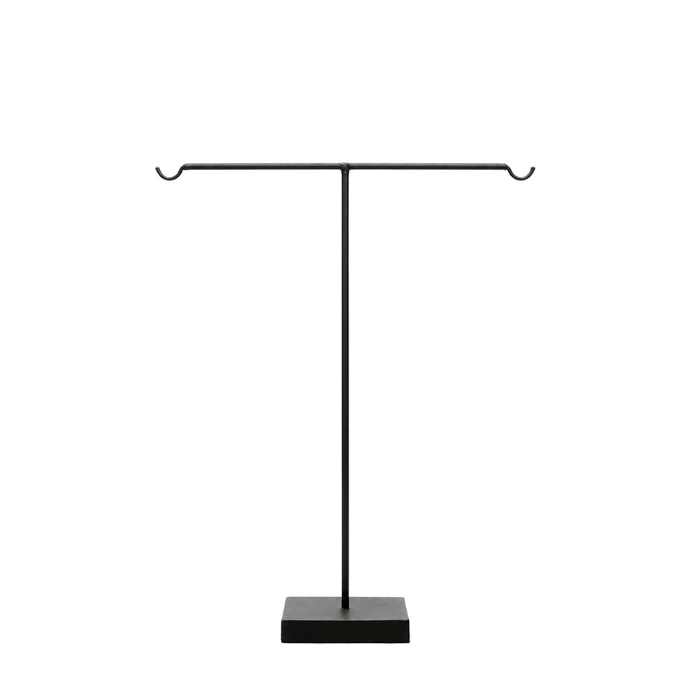 A black metal jewelry and key stand with upward-curved ends and a stable square base.